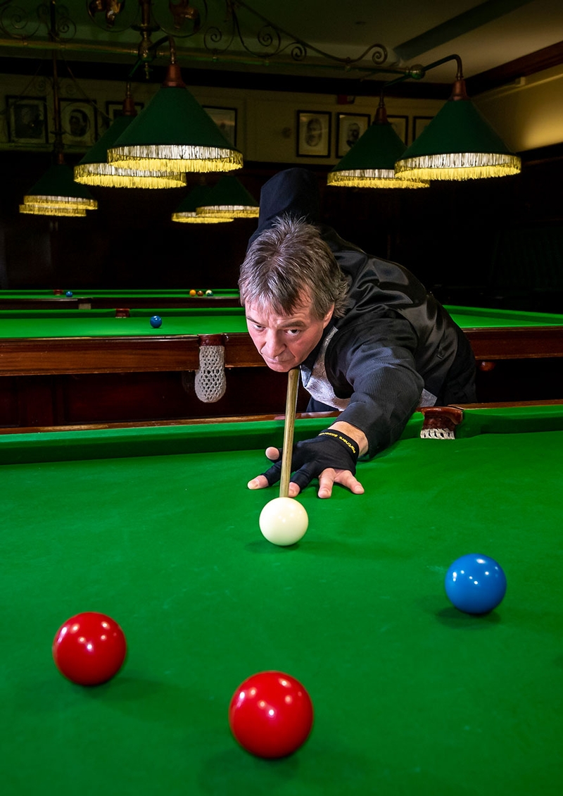 Billiards Professional taking a shot in the billiards room by John Giavedoni.